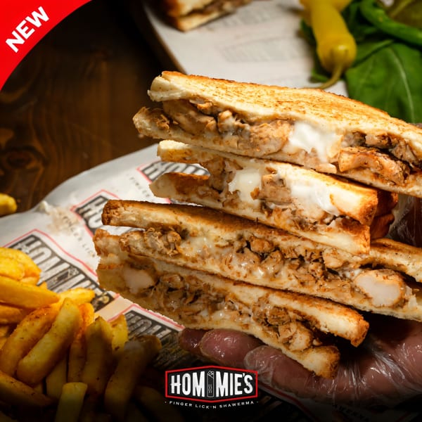 Hommies Shawarma's new chicken shawarma sandwich, cut in half, with fries and peppers.